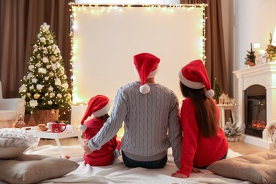 Photo of Family watching movie using video projector at home. Cozy Christmas atmosphere
