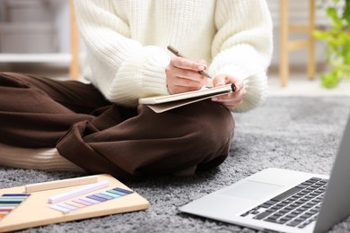 Photo of Woman with planner and laptop on floor indoors, closeup