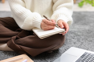 Photo of Woman with planner and laptop on floor indoors, closeup