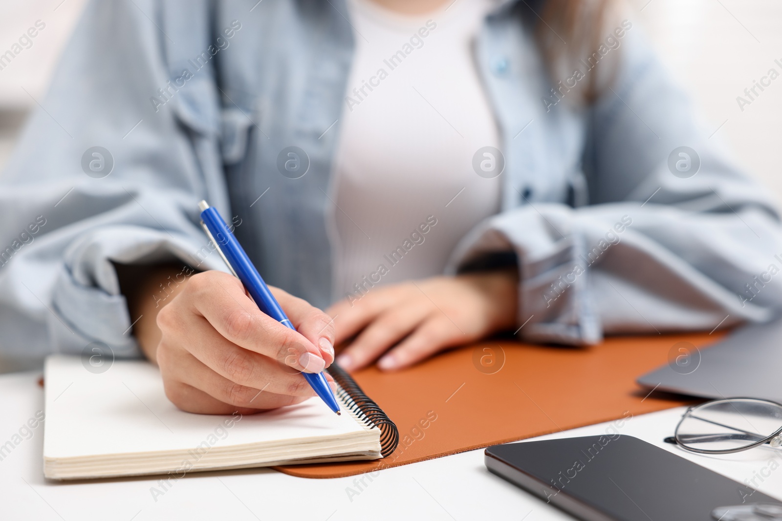 Woman writing in planner at white desk indoors, closeup Photo of Woman writing in planner at white desk indoors, closeup
