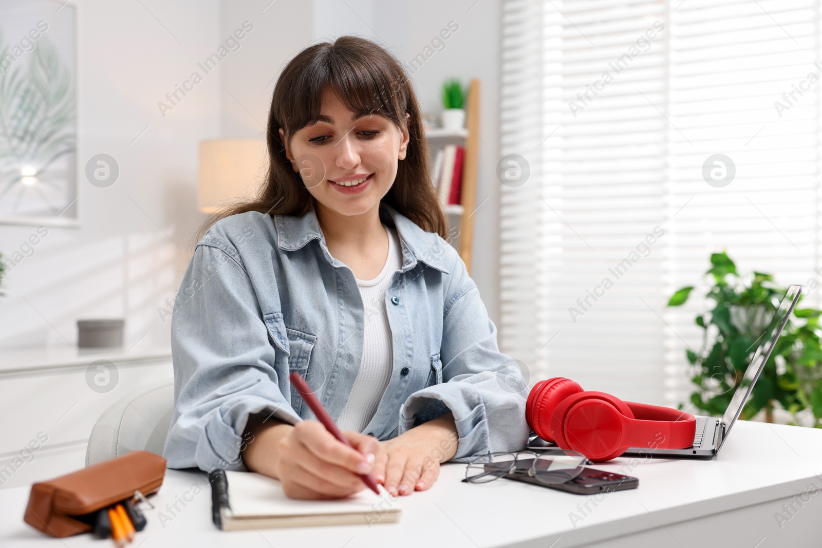 Woman writing in planner at white desk indoors Photo of Woman writing in planner at white desk indoors
