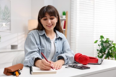 Photo of Woman writing in planner at white desk indoors