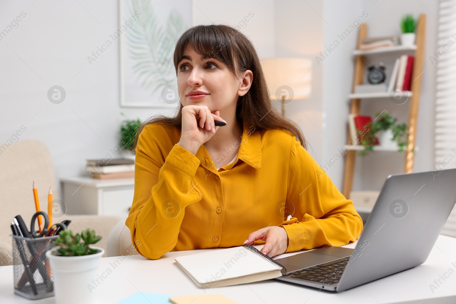 Woman with planner and laptop at white desk indoors Photo of Woman with planner and laptop at white desk indoors