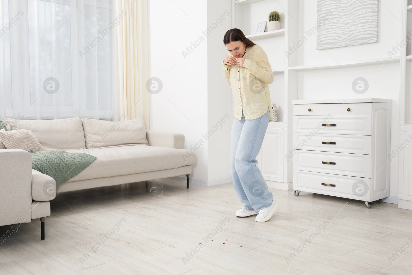 Emotional young woman looking in disgust at cockroaches on floor indoors. Pest problem Photo of Emotional young woman looking in disgust at cockroaches on floor indoors. Pest problem