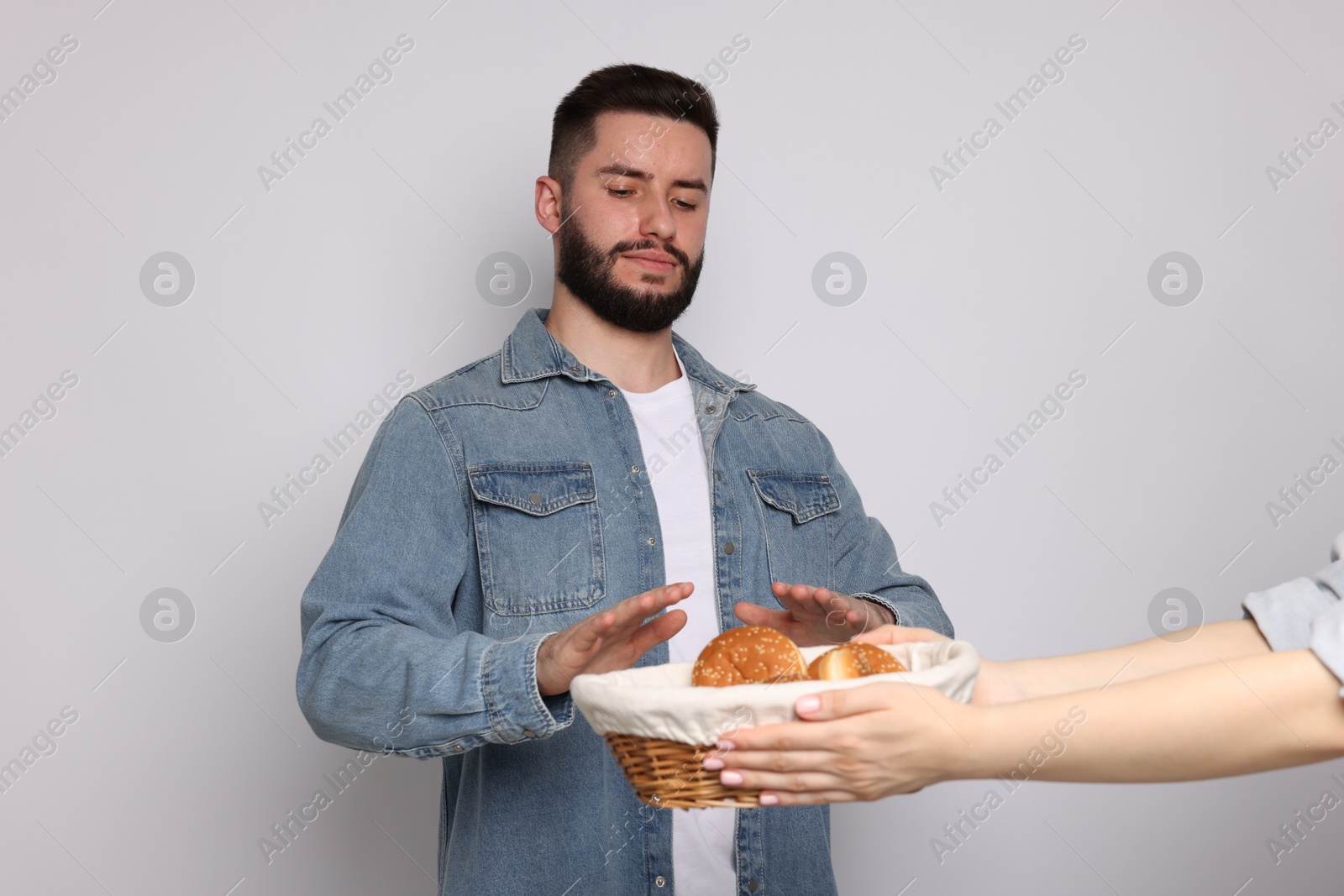 Gluten free diet. Man refusing from pastries on light grey background Photo of Gluten free diet. Man refusing from pastries on light grey background