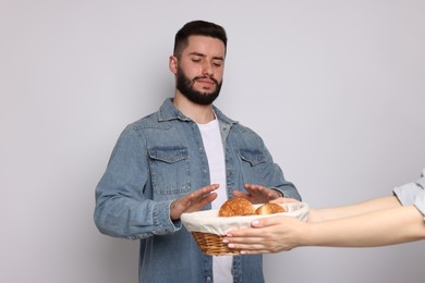 Photo of Gluten free diet. Man refusing from pastries on light grey background
