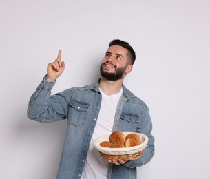Photo of Gluten free diet. Man with pastries pointing at something on light grey background
