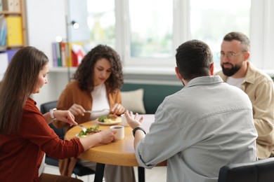 Photo of Colleagues chatting during lunch break in office