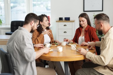 Photo of Colleagues chatting during lunch break in office