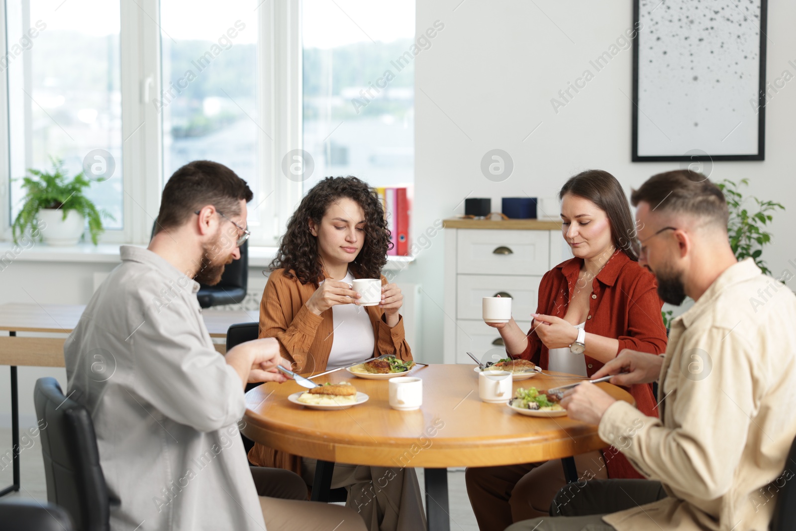 Colleagues chatting during lunch break in office Photo of Colleagues chatting during lunch break in office