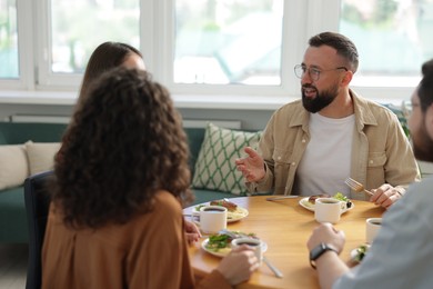 Photo of Colleagues chatting during lunch break in office