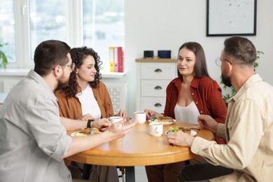 Photo of Colleagues chatting during lunch break in office