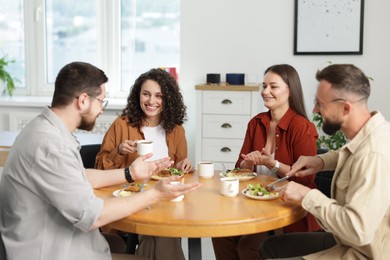 Photo of Colleagues chatting during lunch break in office