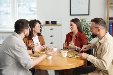 Photo of Colleagues chatting during lunch break in office