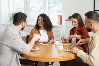 Photo of Colleagues chatting during lunch break in office