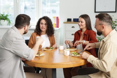 Photo of Colleagues chatting during lunch break in office