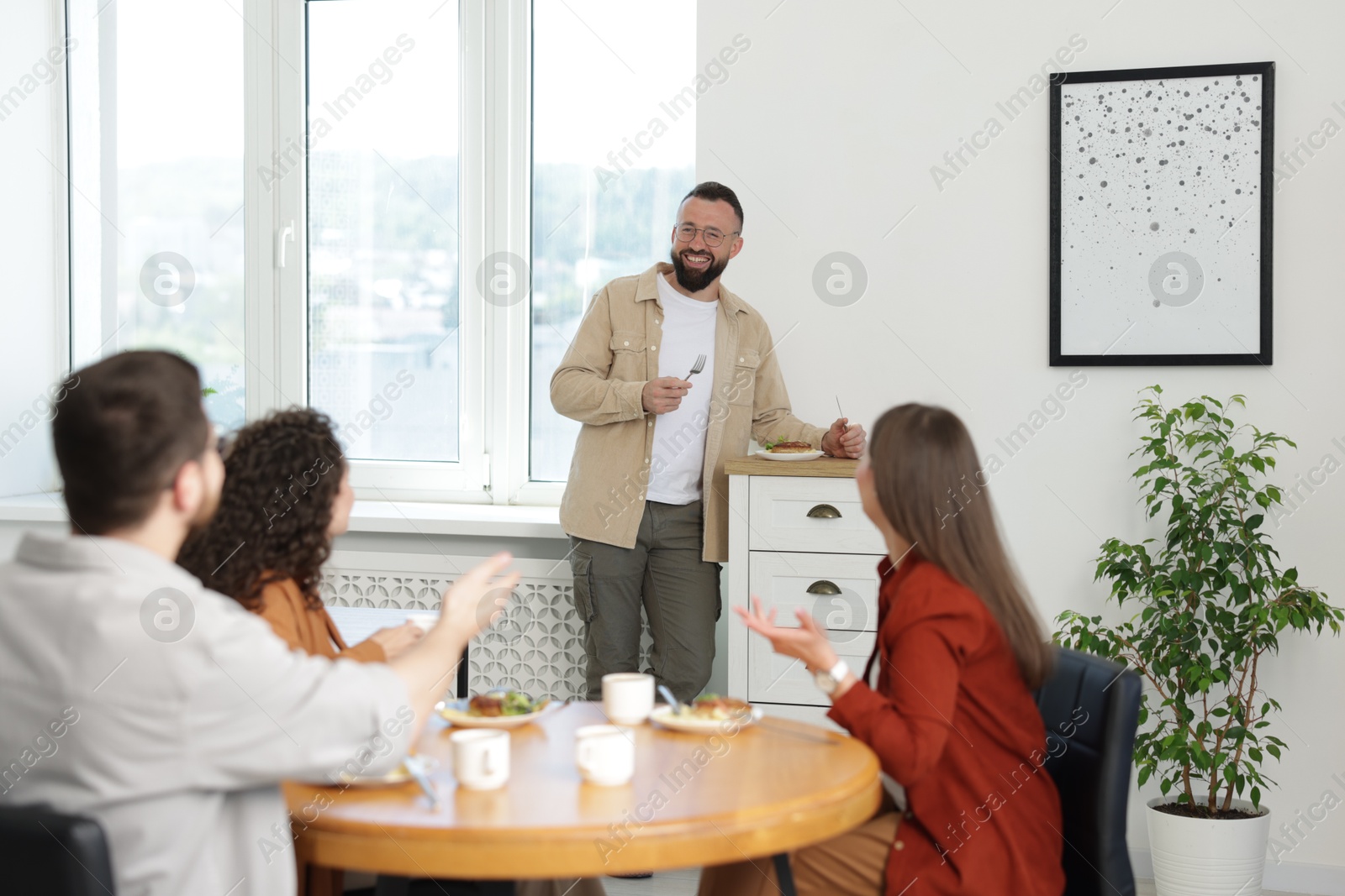 Colleagues chatting during lunch break in office Photo of Colleagues chatting during lunch break in office