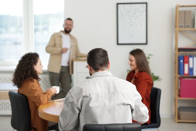 Photo of Colleagues chatting during lunch break in office