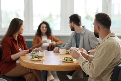 Photo of Colleagues chatting during lunch break in office