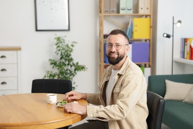 Photo of Man with meal at table during lunch break in office