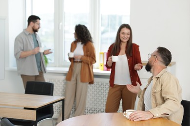 Photo of Colleagues chatting during coffee break in office