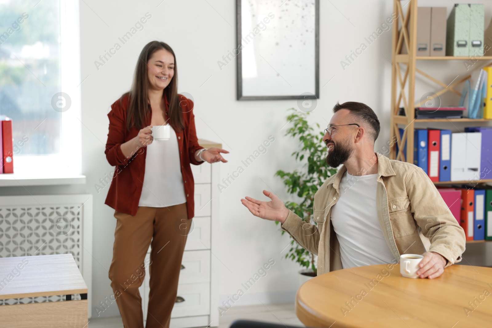 Colleagues chatting during coffee break in office Photo of Colleagues chatting during coffee break in office