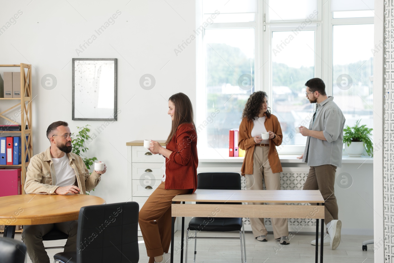 Colleagues chatting during coffee break in office Photo of Colleagues chatting during coffee break in office
