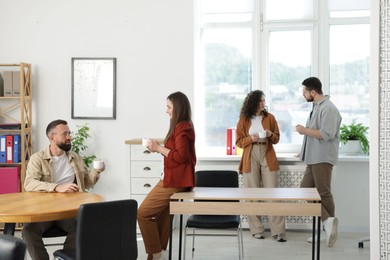 Photo of Colleagues chatting during coffee break in office