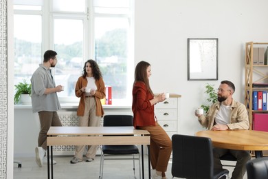 Photo of Colleagues chatting during coffee break in office