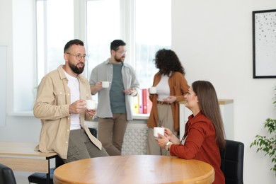 Photo of Colleagues chatting during coffee break in office