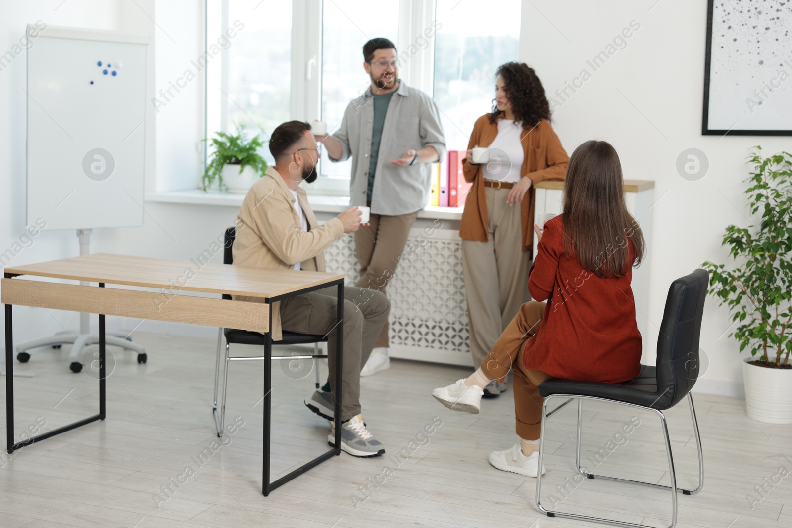 Colleagues chatting during coffee break in office Photo of Colleagues chatting during coffee break in office