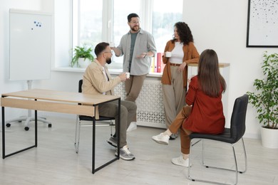 Photo of Colleagues chatting during coffee break in office