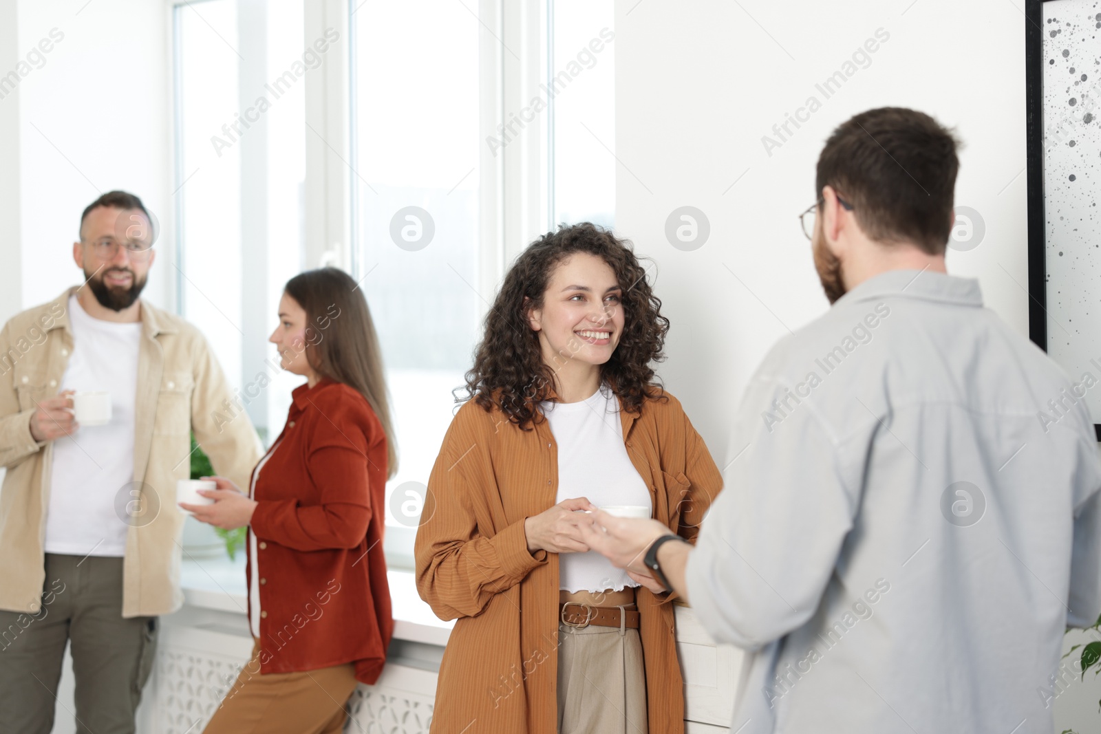 Colleagues chatting during coffee break in office Photo of Colleagues chatting during coffee break in office