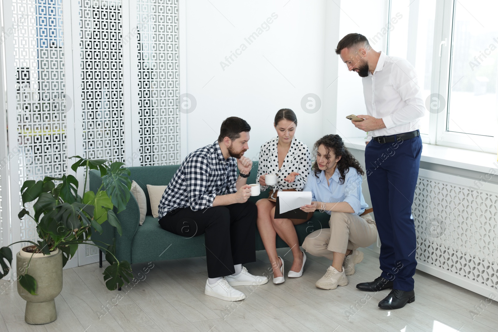 Colleagues chatting during coffee break in office Photo of Colleagues chatting during coffee break in office