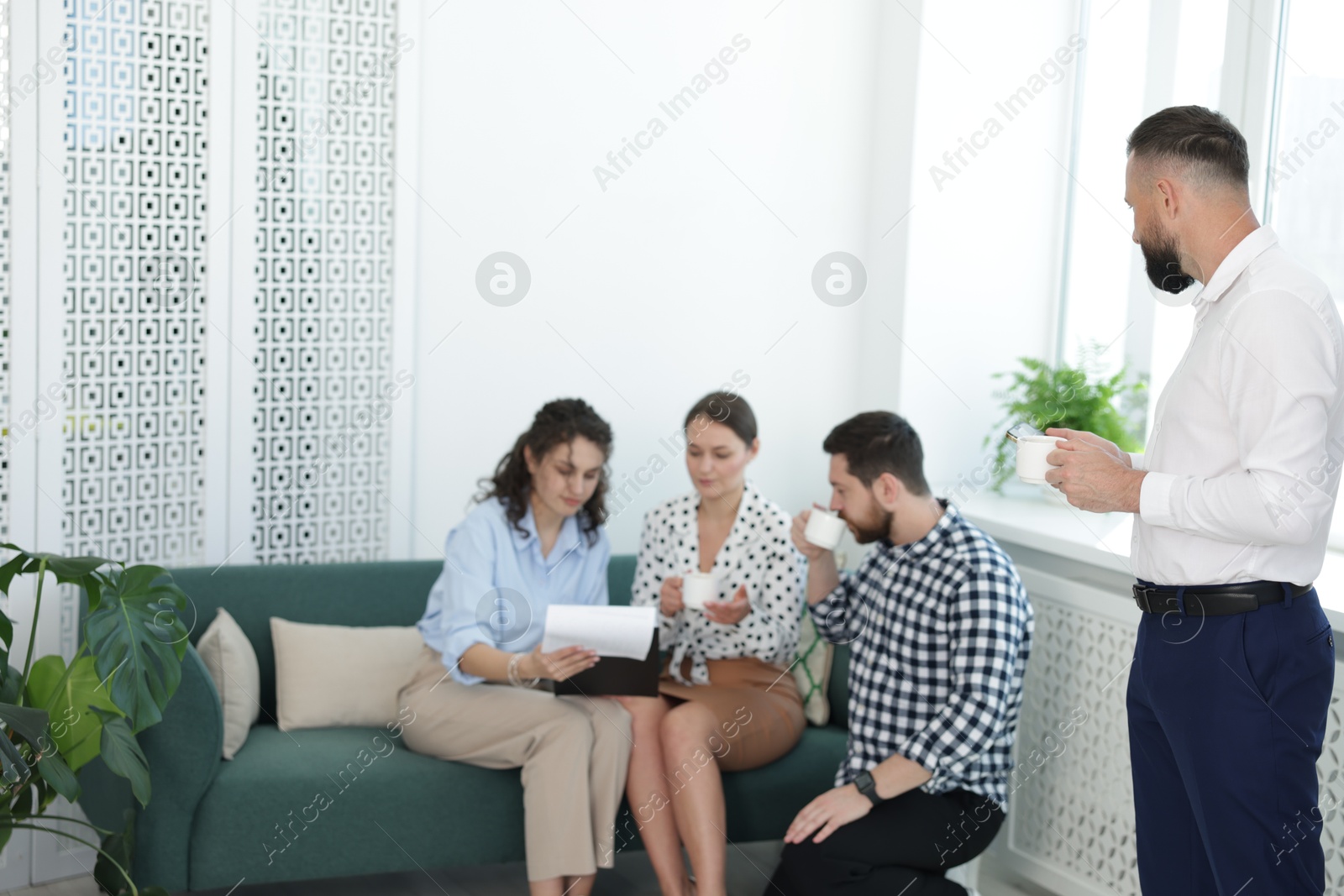 Colleagues chatting during coffee break in office. Space for text Photo of Colleagues chatting during coffee break in office. Space for text