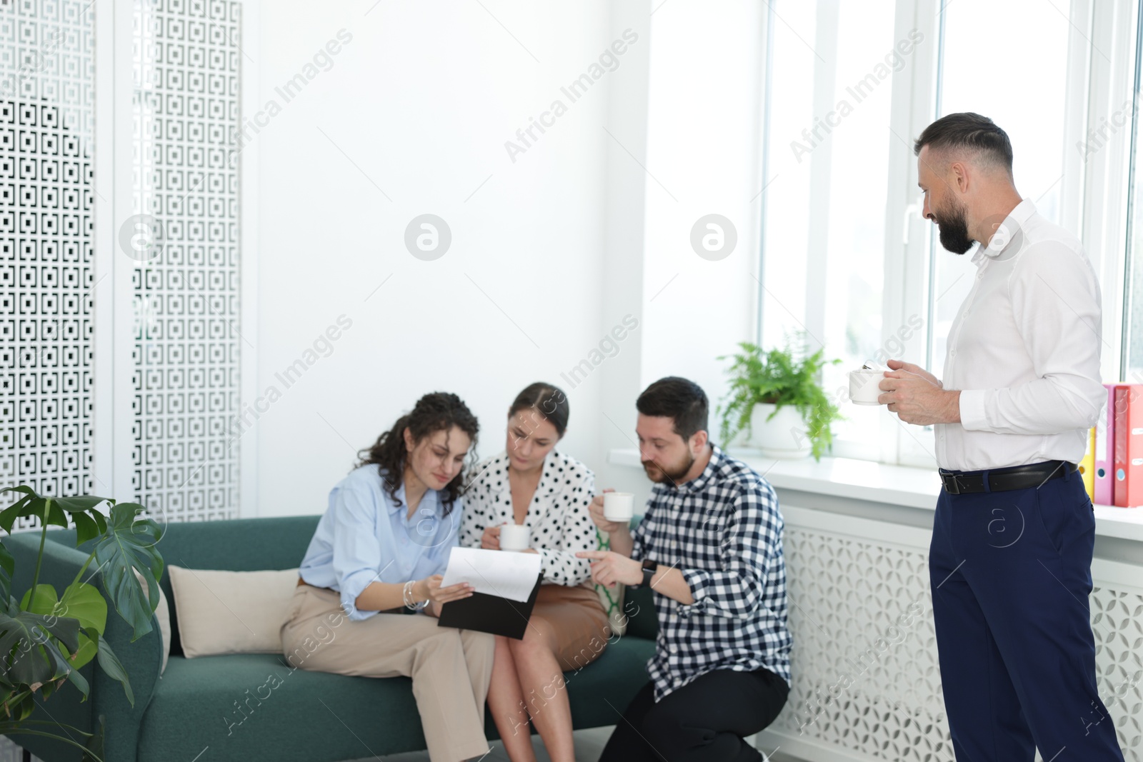 Colleagues chatting during coffee break in office. Space for text Photo of Colleagues chatting during coffee break in office. Space for text