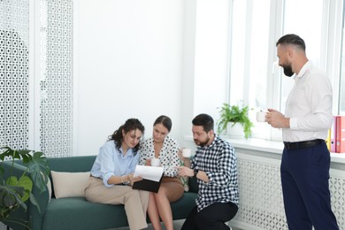 Photo of Colleagues chatting during coffee break in office. Space for text