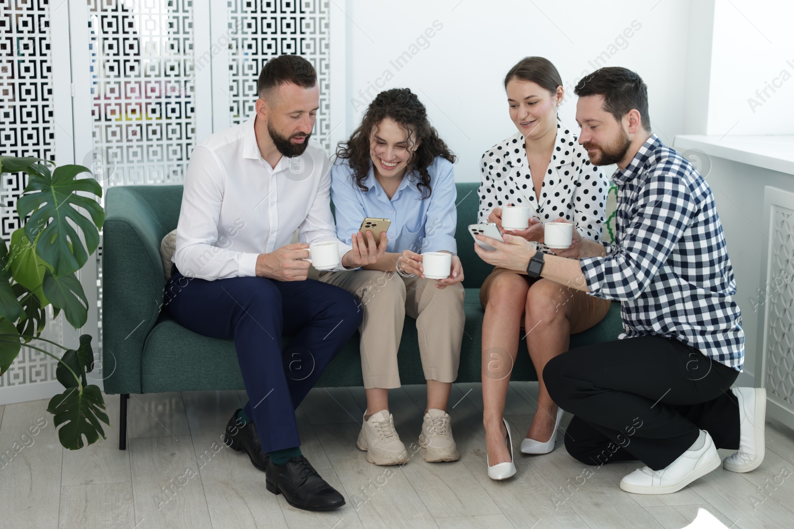 Colleagues with coffee and smartphones during break in office Photo of Colleagues with coffee and smartphones during break in office
