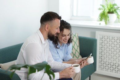Photo of Man showing colleague something on his phone during coffee break in office