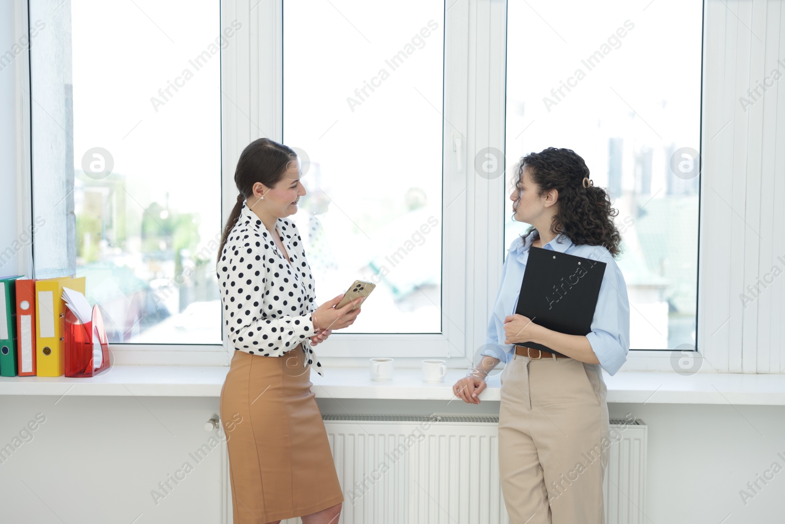 Colleagues discussing work during coffee break in office Photo of Colleagues discussing work during coffee break in office