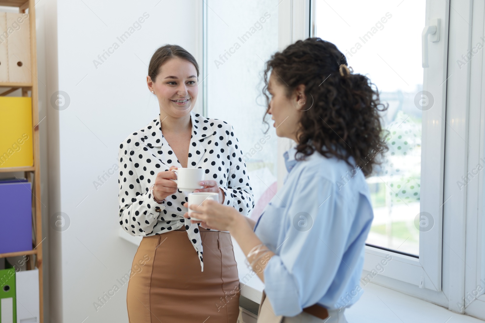 Colleagues chatting during coffee break in office Photo of Colleagues chatting during coffee break in office