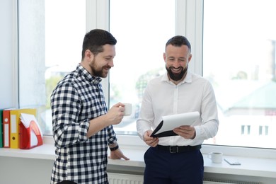 Photo of Colleagues with coffee and paperwork during lunch break in office