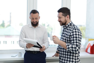 Photo of Colleagues with coffee and paperwork during lunch break in office