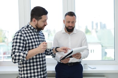 Photo of Colleagues with coffee and paperwork during lunch break in office