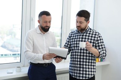 Photo of Colleagues with coffee and paperwork during lunch break in office