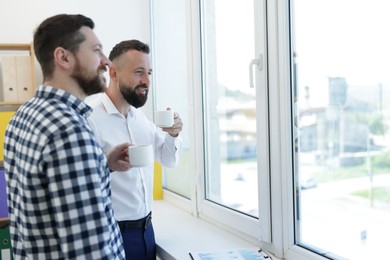Photo of Colleagues looking out window during coffee break in office