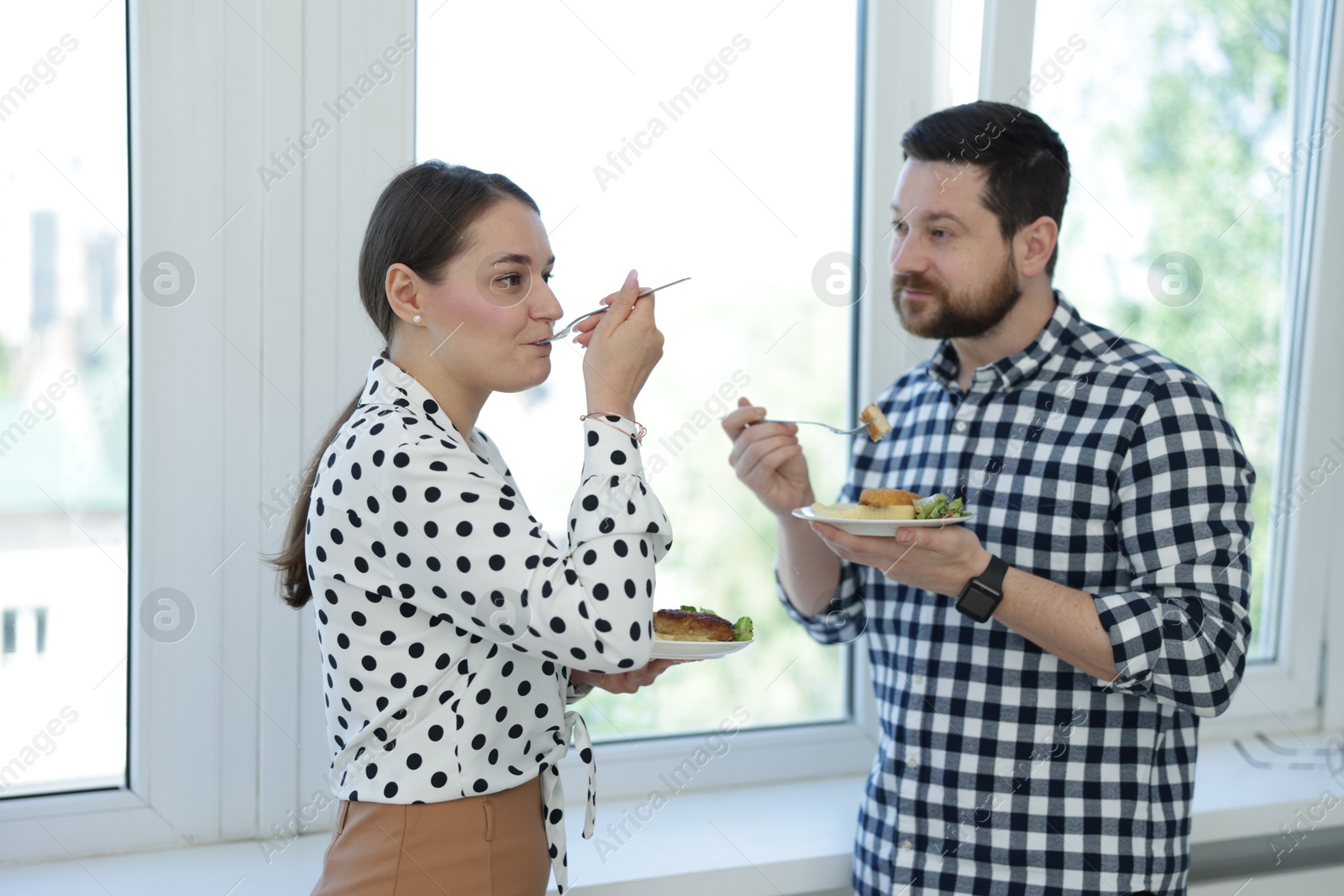 Colleagues with food near window in office during lunch break Photo of Colleagues with food near window in office during lunch break