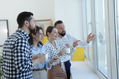 Photo of Colleagues looking out window during coffee break in office