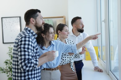 Photo of Colleagues looking out window during coffee break in office