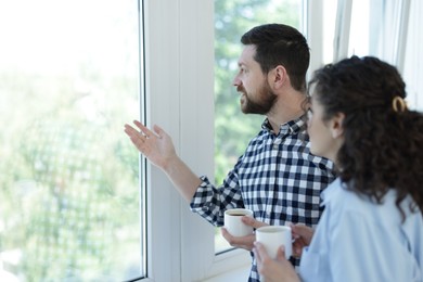 Photo of Colleagues looking out window during coffee break in office